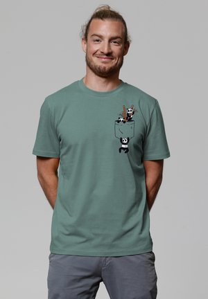 Green cotton t-shirt featuring a pocket graphic with three playful pandas, two holding pencils and one hanging from the pocket.