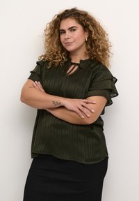 Haut plissé vert foncé avec des manches à volants, décolleté rond et détail en forme de clé. Le tissu a une texture lisse et une silhouette fluide.