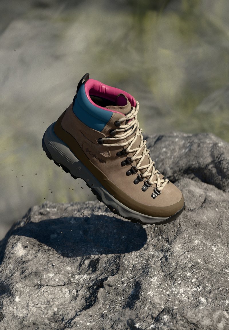 Brown hiking boot with blue and pink accents, featuring a textured upper, gray rubber sole, and prominent lacing system.