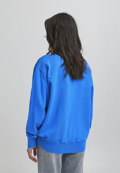 Blå oversized sweatshirt laget av myk stoff, med ribbestrikkede mansjetter og nederkant. Designet har drop shoulder og en glatt tekstur.