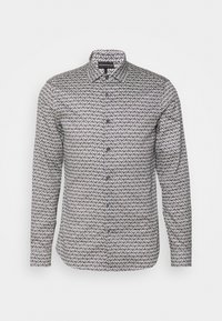 Pitkähihainen paita, jossa on mustavalkoinen geometrinen kuvio, napitettu etuosa ja perinteinen kaulus. Puuvillakangasta, jossa on sileä pinta.