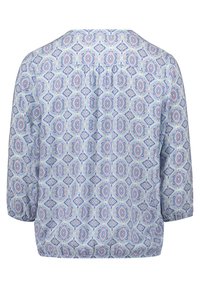 Blouse à motifs avec un fond bleu clair orné de formes circulaires et en losange en rose et bleu. Son design comprend un col rond et des manches trois-quarts.