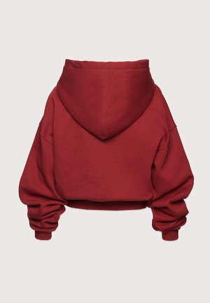 Skrojona czerwona bluza z kapturem, charakteryzująca się długimi, luźnymi rękawami i ściągaczami przy nadgarstkach. Gładka tekstura i minimalistyczny design bez widocznych detali.