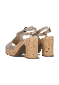 Beige high-heeled sandals with a textured upper, adjustable ankle strap, and cork block heels. Features cutouts and a smooth sole.