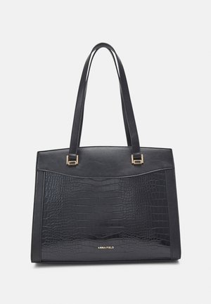 Bolso rectangular negro con textura de cocodrilo en el panel frontal, dos asas largas, herrajes dorados y logo "ANNA FIELD" en el centro inferior.