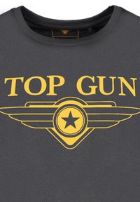Graues T-Shirt mit auffälligem gelbem Schriftzug "TOP GUN" und einem geflügelten Stern-Grafik. Das Material wirkt weich mit einer glatten Textur.