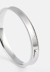 Pulsera de plata con una superficie lisa y un borde texturizado de cuentas. Cuenta con un pequeño cierre para un cierre seguro.