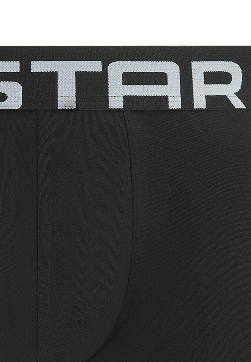 Zwarte boxershorts met een brede elastische tailleband met witte "STAR" letters, gemaakt van een gladde, rekbare stof.