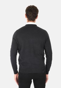 Maglione a maglia grigio scuro con maniche lunghe, scollo rotondo e orlo a costine. La vista posteriore mostra una texture liscia e un design aderente.