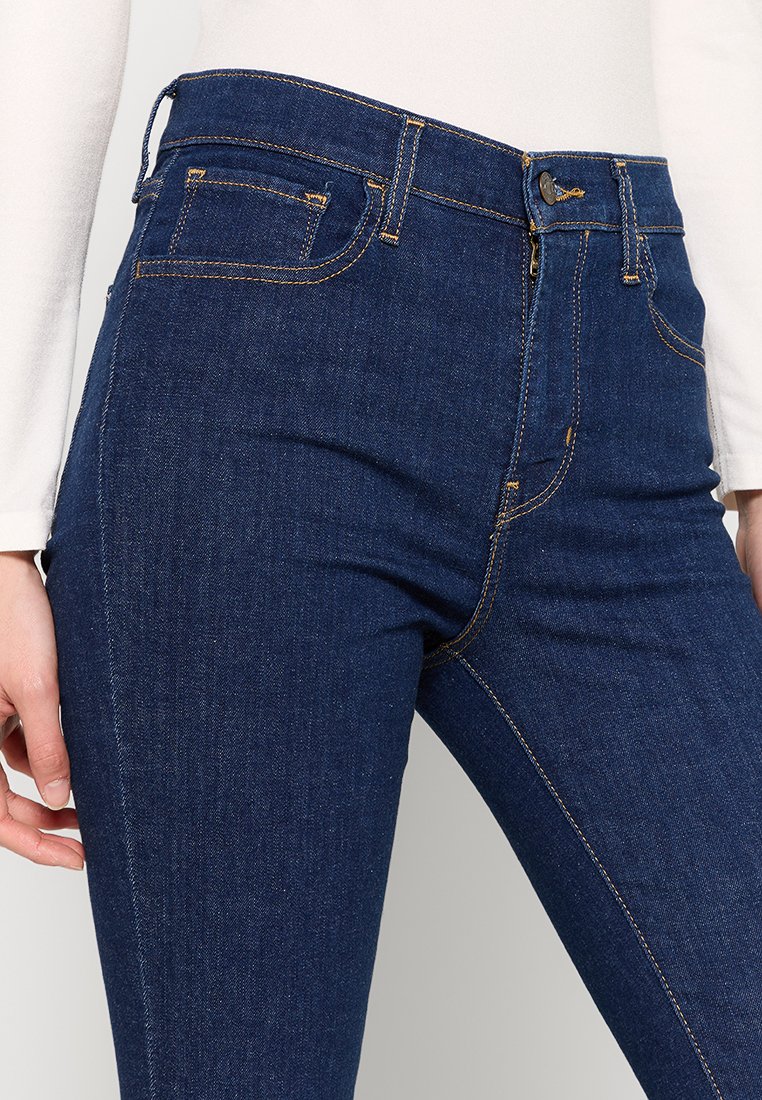 Dunkelblaue Skinny-Jeans aus Denim, mit kontrastierenden Nähten, einem vorderen Knopf- und Reißverschluss sowie vorderen und hinteren Taschen.