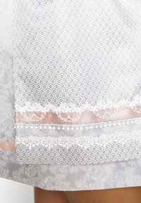 Robe bleu clair avec des motifs blancs complexes, bordure en dentelle et accents de ruban rose. Présente des textures délicates et des éléments de design en couches.