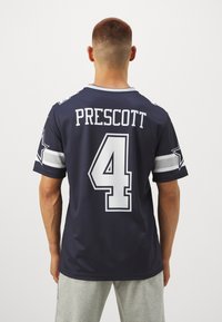 Tengerészkék sportmez, fehér részletekkel, a hátsó oldalán feltűnően "PRESCOTT" név és "4" szám látható, lélegző anyagból készült.
