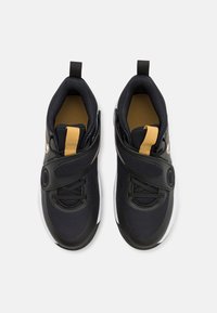 Mustat urheilukengät, joilla on verkkopinta, harmaita yksityiskohtia, tarranauha ja pyöreä nauhoitusjärjestelmä. Valkoinen pohja, jossa on teksturoitu pito.