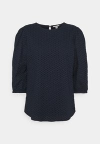 Blouse bleu marine avec manches bouffantes trois-quarts, tissu texturé présentant un motif en losange, encolure ronde et détail dos avec ouverture en forme de goutte.