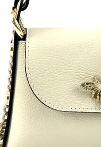 Beige leren handtas met een gestructureerd oppervlak, voorzien van een gouden vlinder-sluiting en kettingband. Flapsluiting en subtiele stiksels.