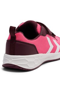 Różowy but sportowy z siateczkową cholewką, ciemnogranatowymi akcentami, paskiem na rzep oraz białą gumową podeszwą z sześciokątnym wzorem.