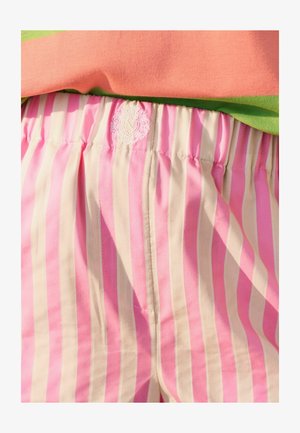 Shorts en tissu rayé rose et crème avec une taille élastique. Comprend un logo brodé sur la taille. Texture lisse.