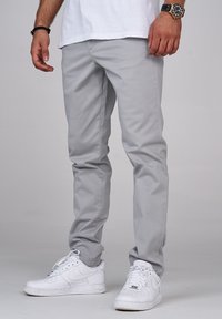 Grå bomullschinos med slim fit, platt front och sidofickor, tillsammans med vita sneakers. Enkel design, mjuk textur och utan dekorationer.