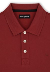 Czerwona koszulka polo z trzema guzikami, dzianinową fakturą, kontrastowym czarnym kołnierzykiem oraz subtelnym logo z przodu.