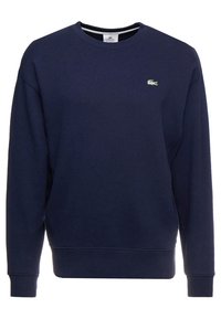 Sudadera de algodón azul marino con cuello redondo acanalado, mangas largas y un pequeño logo verde en el pecho izquierdo. Tejido suave y texturizado.