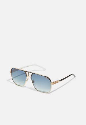 Óculos de sol em metal tom de ouro com lentes gradientes azuis. Grande formato angular, apresentando uma ponte dupla e braços contrastantes em preto e branco.