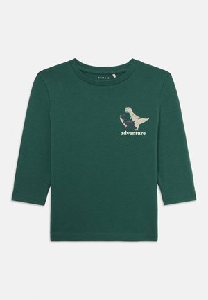 Roheline pikkade varrukatega T-särk, mis on valmistatud pehmest puuvillast, dinosauruse graafika ja sõnaga "seiklus" trükituna valgend.