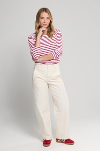 Rød og hvid stribet langærmet skjorte med tætsiddende liv, parret med hvide vide bukser og røde sneakers. Simpelt design med afslappet pasform.