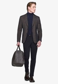 Brunternet blazer over en navy kabelstrik turtleneck, mørke bukser, brun lædertaske og polerede sko, der fremhæver strukturerede materialer.