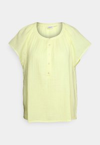Blusa amarela de manga curta feita de tecido leve. Apresenta um decote redondo e uma abertura com botões, com um corte solto e uma superfície texturizada.