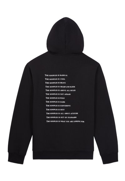 Must mustaga mustmüts mustakuubik valge teksti taga mitmete fraasidega "The Kooples", valmistatud pehmest, tekstureeritud kangast.