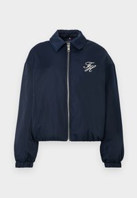 Navy blue zip-up striukė su elastingomis rankovėmis, apykakle ir baltais siuviniais inialais "FH" kairėje krūtinės pusėje.