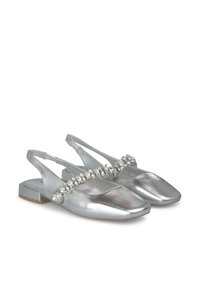 Scarpe slingback metalliche argento con punta quadrata, decorate con una fascia di strass decorativa. Tacco a blocco solido per stabilità.