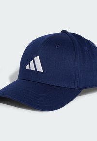 Navy blue cap made of fabric, featuring a curved visor and six-panel design. White three-stripe logo on the front, with stitched details.