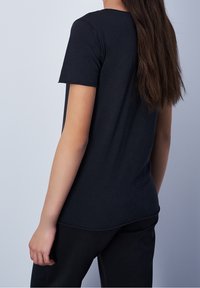 Černé tričko s krátkým rukávem vyrobené z měkké bavlny, s kulatým výstřihem a rovným lemem. Minimalistický design, bezšvový zadní díl.
