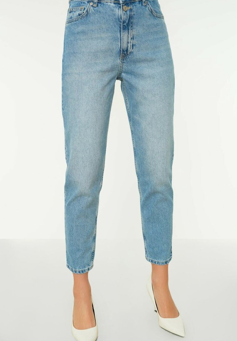 Jeans de tiro alto en azul claro con pierna ajustada, que presentan un diseño clásico de cinco bolsillos y cierre de botón metálico. Textura de mezclilla suave.