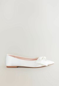 Ballerines en satin blanc avec un bout pointu et un nœud décoratif sur le dessus. La semelle est plate et en matériau beige.