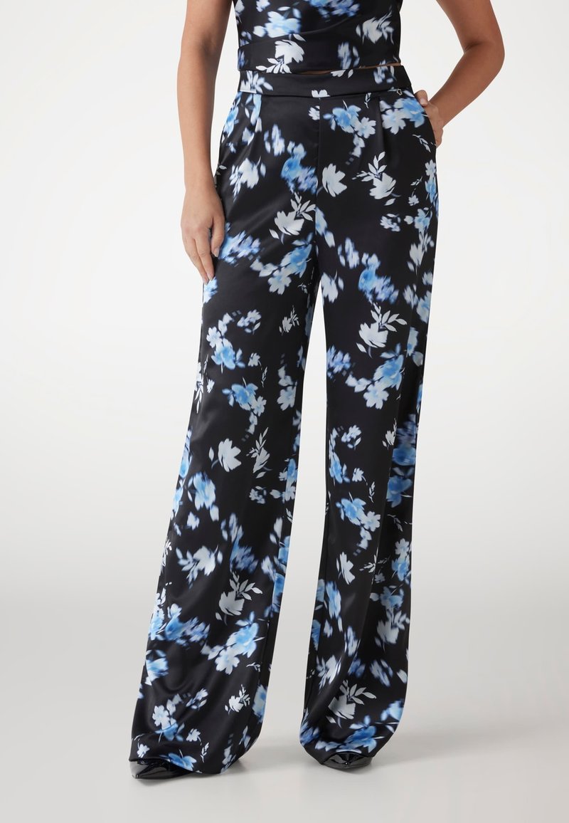 Pantaloni largi din satin negru cu motive florale albastre și albe, talie înaltă și buzunare laterale. Textură netedă.