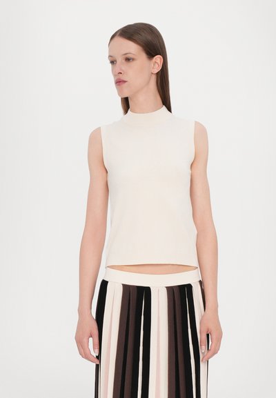 Cream sleeveless top with a high neckline, soft texture, paired with a black and cream striped pleated skirt. Simple and minimalistic design.