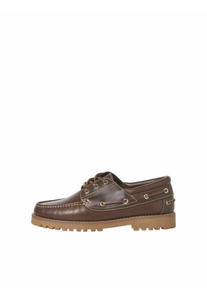 Zapato náutico de cuero marrón con suela de goma beige, cierre delantero de cordones, y costuras y ojales decorativos a lo largo de los costados.