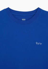 T-shirt Levi's bleu à col rond avec le texte brodé "Paris" en blanc sur le côté gauche de la poitrine.