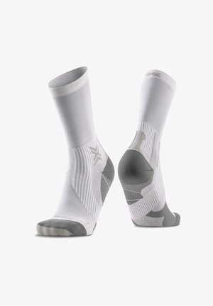 Par de calcetines deportivos blancos de caña media con detalles grises en talones, dedos y arcos sobre un fondo blanco.