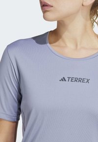 Lichtpaarse t-shirt met korte mouwen, gemaakt van een gladde stof, met een zwart "TERREX" logo op de borst en een ronde halslijn.