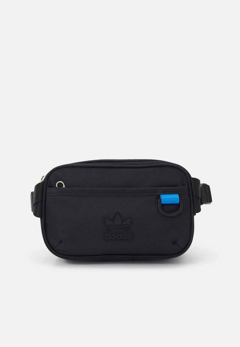 Černá ledvinka Adidas s přední kapsou na zip, nenápadným logem, modrou smyčkou na pásku a nastavitelností bočního uzávěru na bílém pozadí.