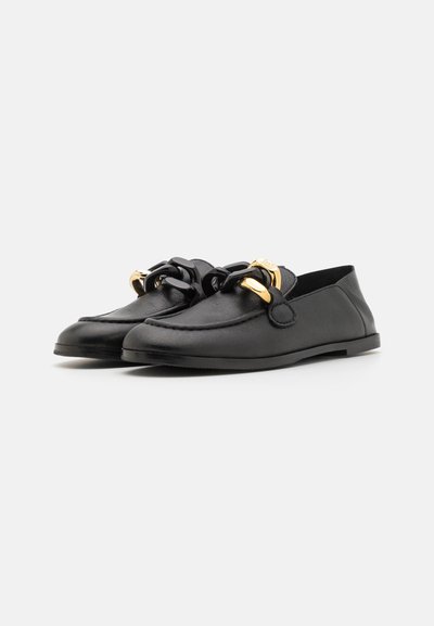 Mocasines de cuero negro con cadena decorativa y acentos dorados, suela plana, textura suave y un diseño minimalista.