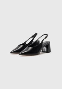 Scarpe slingback in pelle nera con punta affusolata, lati aperti e tacco quadrato chunky. Presentano una cintura regolabile per una vestibilità perfetta.