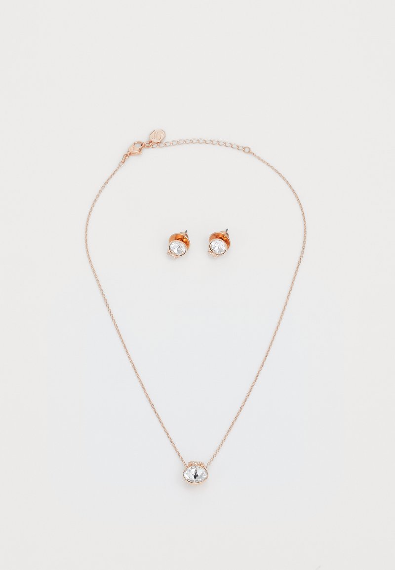 Sada šperků v růžovém zlatě, která obsahuje řetízkový náhrdelník se středovým přívěskem z čirého drahokamu a odpovídající náušnice s čirými kameny.
