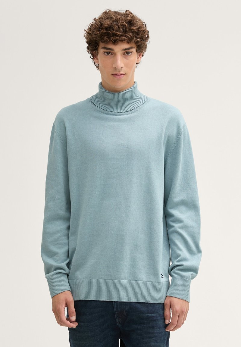 Hellblauer, gestrickter Rollkragenpullover mit gerippten Bündchen und Saum, entspannte Passform, aus weichem Material gefertigt, mit einem kleinen Logo nahe dem Saum.