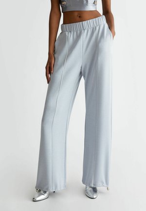 Pantaloni a gamba larga di un blu chiaro, caratterizzati da una texture morbida, con una cintura elastica, tasche laterali e dettagli a piping bianco a contrasto.