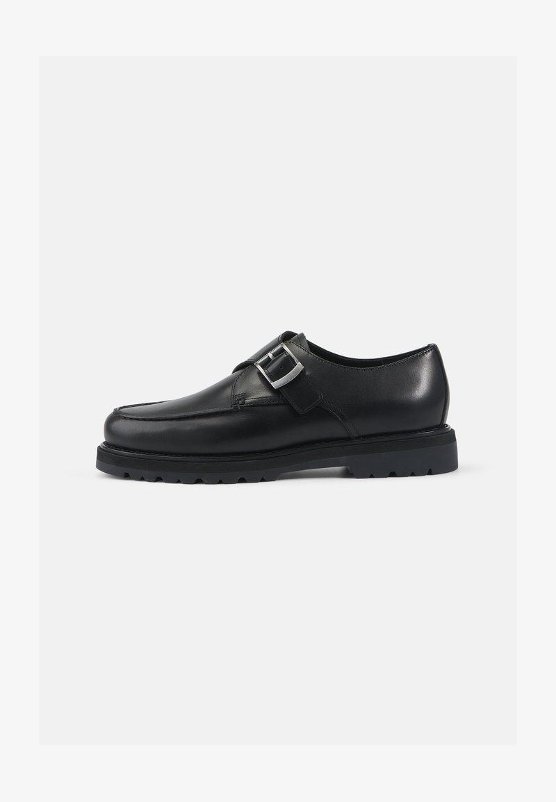 Sapato de couro preto com acabamento liso, forma arredondada e detalhe de fivela prateada. Sola grossa preta com tração.