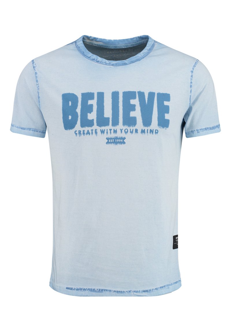 Lichtblauwe katoenen t-shirt met vet blauwe tekst "BLAUW" en "CREËER MET JE GEEST." Ruwe zoomdetails op de mouwen en onderrand.